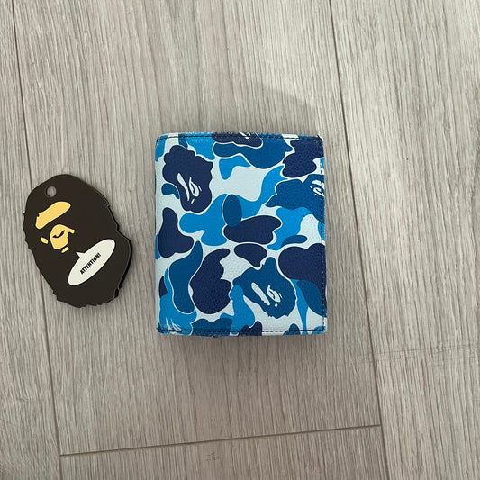 Blue camouflage wallet and black and yellow logo tag on a wooden surface