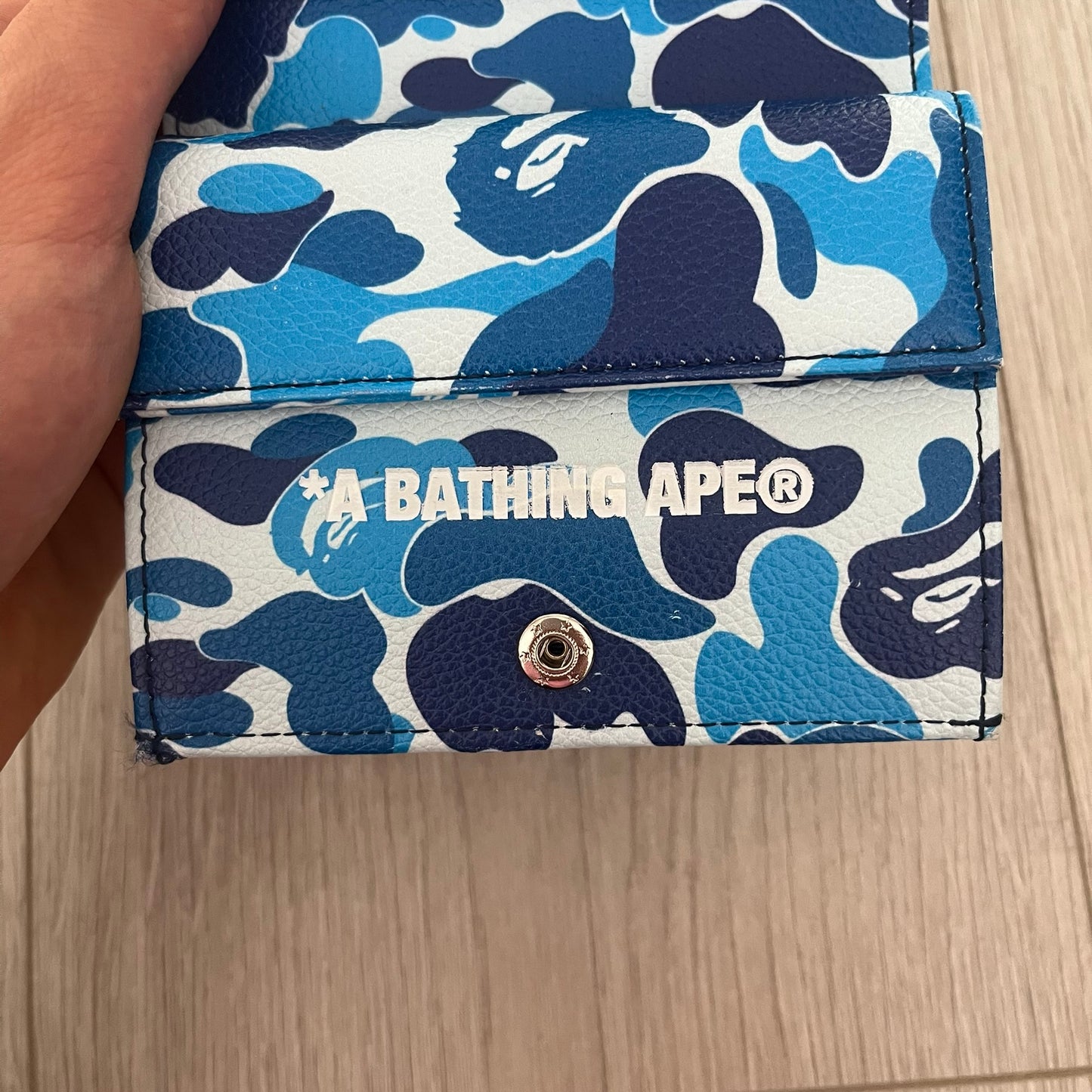 Blue and white camouflage wallet with BAPE logo on a wooden surface