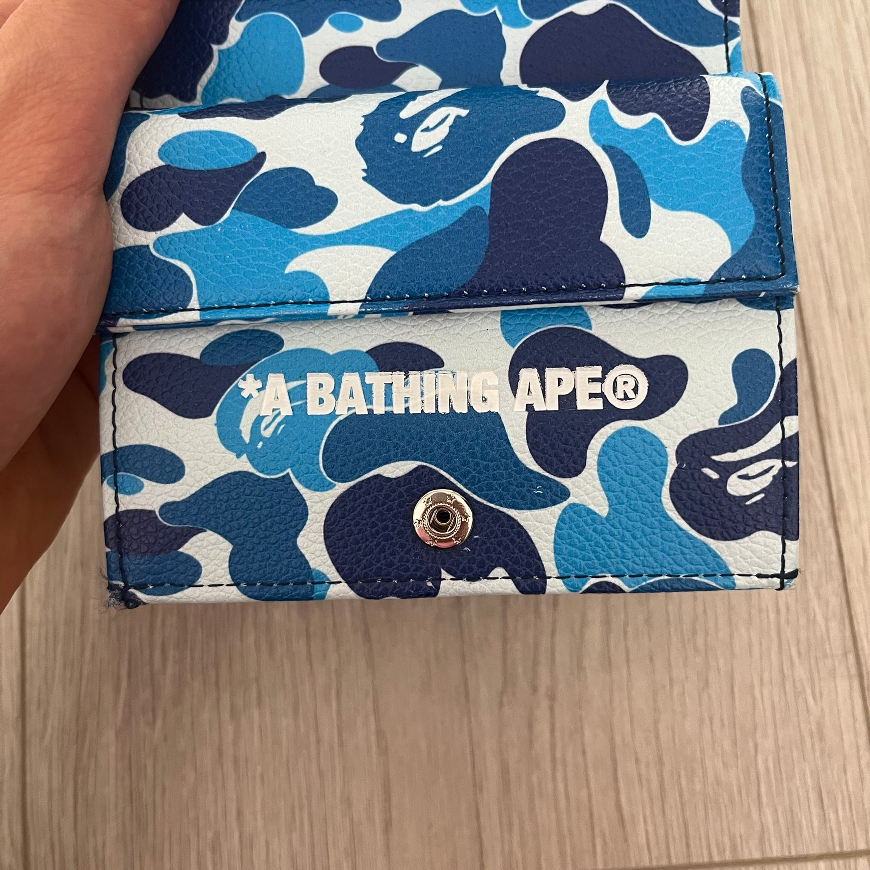 Blue and white camouflage wallet with BAPE logo on a wooden surface