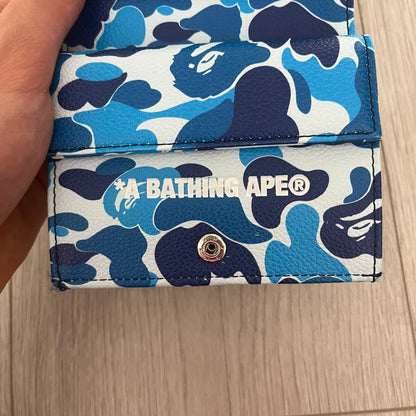Blue and white camouflage wallet with BAPE logo on a wooden surface