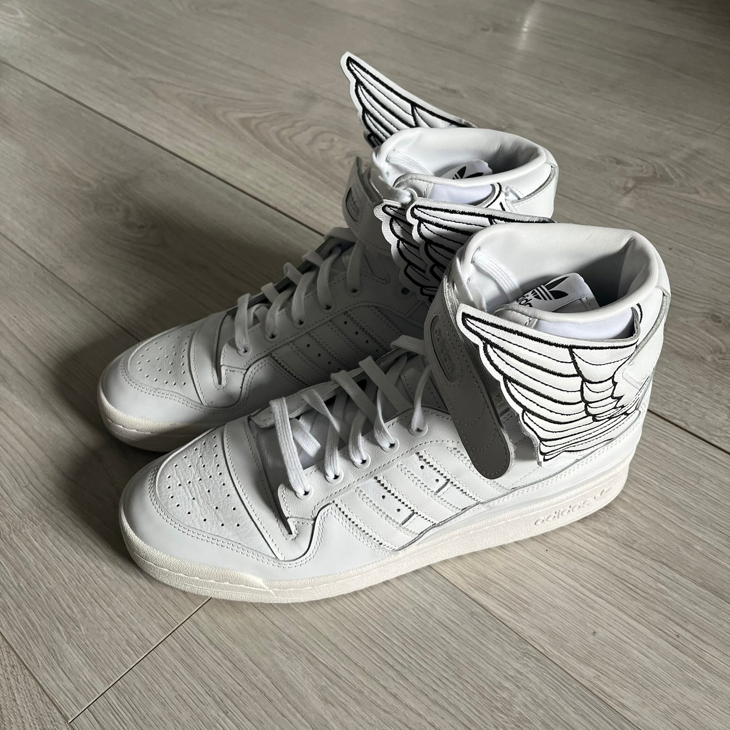 The Adidas Jeremy Scott Wings 4.0 Forum Hi launched on May 5, 2022, in a white and black colorway. Premium leather uppers highlight black stripes, heel tab, and Wings branding, while the high-top structure provides support with a padded collar and tongue. Equipped with a rubber herringbone outsole for grip, this limited edition release merges classic silhouette with JS design.
