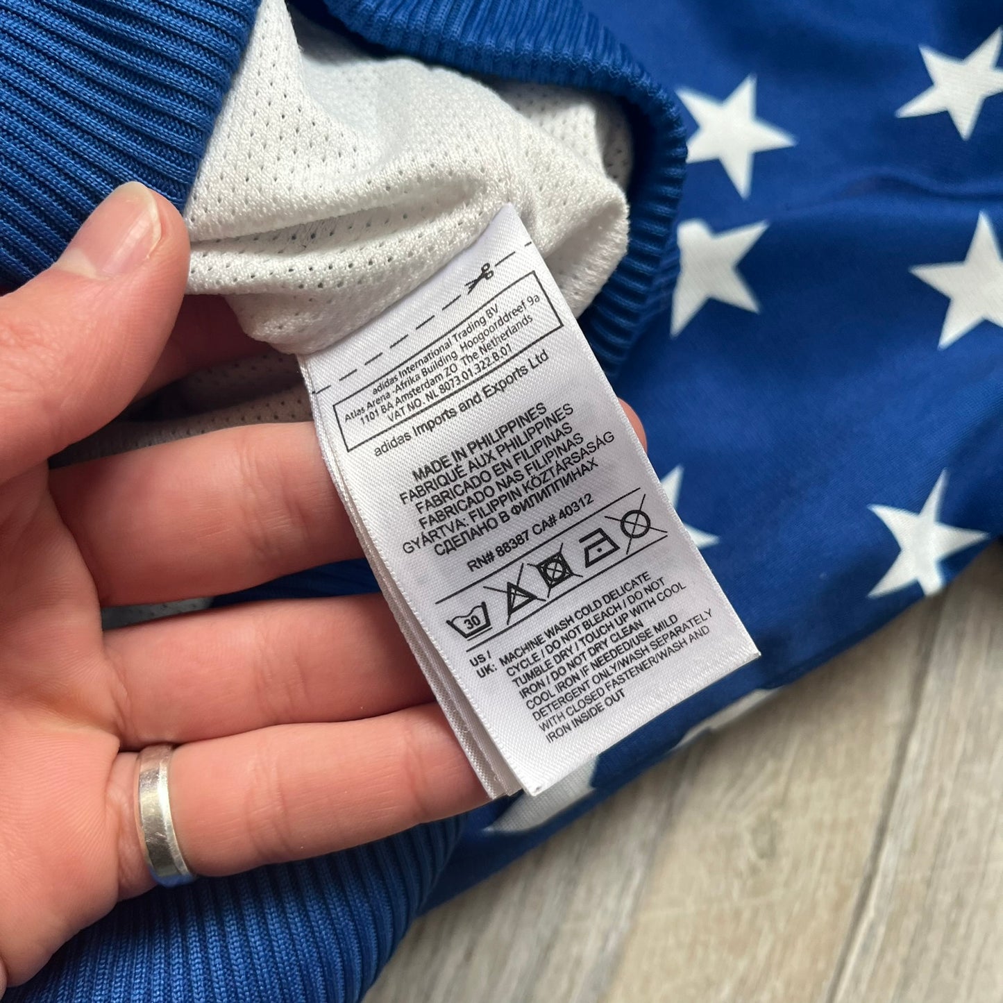 Adidas Originals Stars Blue Track Jacket is a blue zip-up track jacket featuring an all-over white star print. It includes white Adidas three-stripes along the sleeves and a small Adidas Originals patch on the chest. The design closely resembles star-pattern track jacket by Jeremy Scott for Adidas Originals.