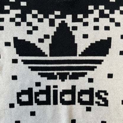 adidas Originals by Jeremy Scott 2013 Pixel Sweater features a white construction with a black upper section that transitions into a pixelated pattern, with black pixels appearing to fall down across the white body. The same pixelated design continues on the back, while the front has a pixelated adidas Trefoil logo. Part of the SS13 collection.
