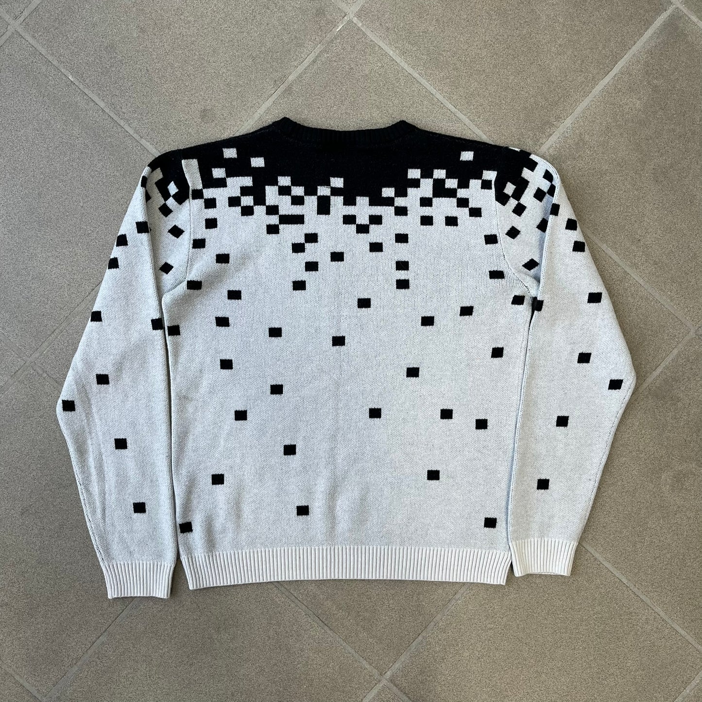 adidas Originals by Jeremy Scott 2013 Pixel Sweater features a white construction with a black upper section that transitions into a pixelated pattern, with black pixels appearing to fall down across the white body. The same pixelated design continues on the back, while the front has a pixelated adidas Trefoil logo. Part of the SS13 collection.
