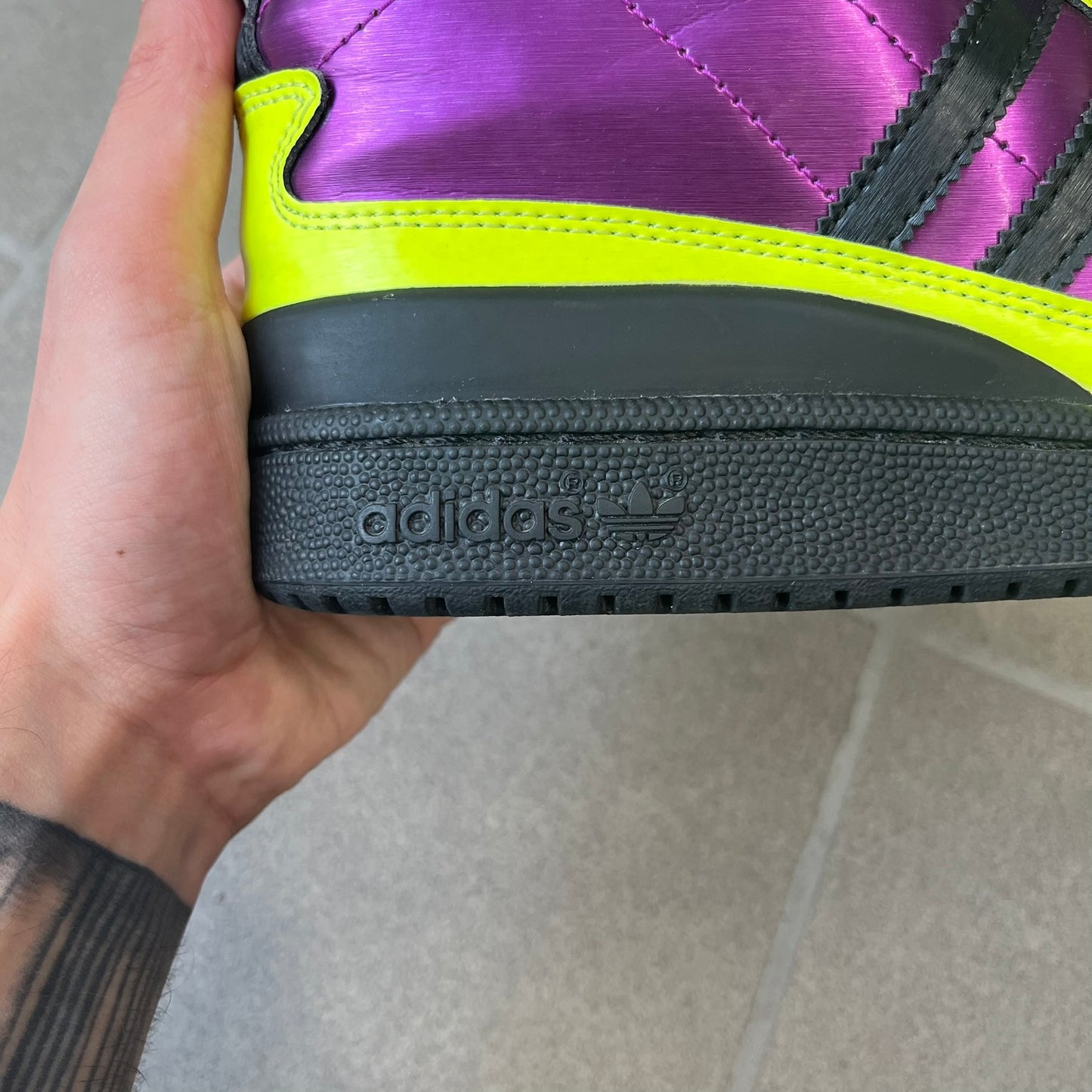 adidas Originals by Jeremy Scott 2014 JS Tall Boy Summer Sneakers feature a yellow and metallic purple high-top construction with a patent-effect synthetic upper. The design has an oversized foldable tongue, ribbed lining, ankle zipper, and abrasion-resistant rubber sole. Part of the adidas Originals by Jeremy Scott SS14 collection.
