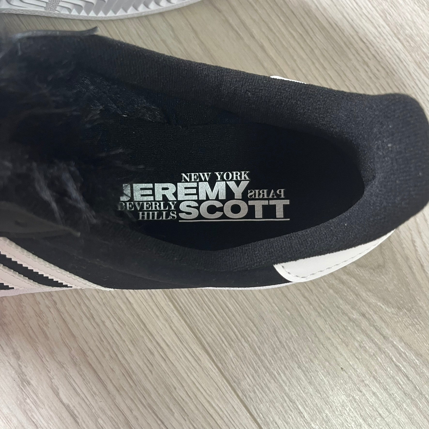 jeremy scott’s take on the adidas campus 80s includes black leather, serrated stripes, and unique faux fur tongues. detachable white bones on the laces add a customizable, standout touch. this 2023 release balances classic style with avant-garde details.