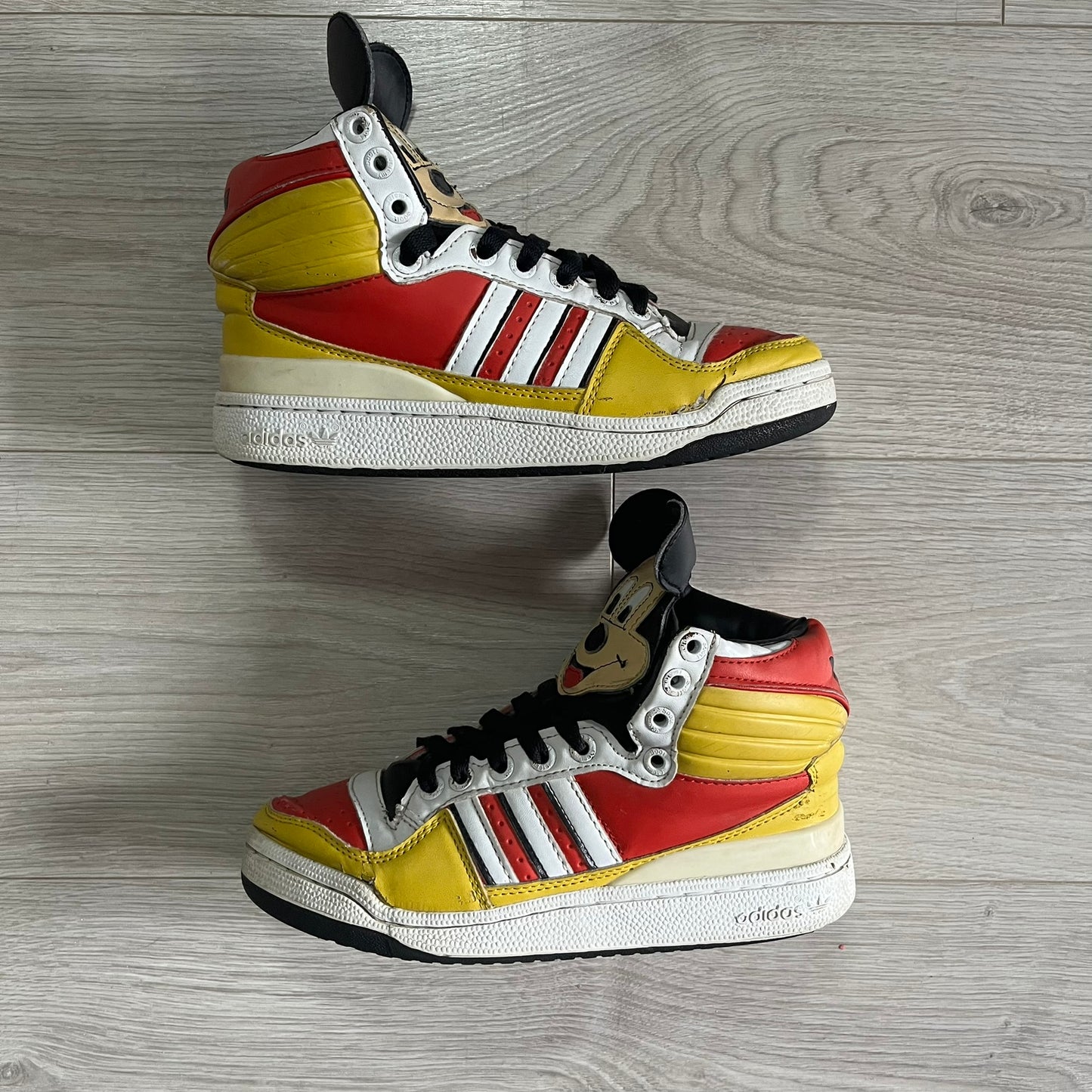 Pair of Adidas sneakers with a colorful design on a wooden floor.