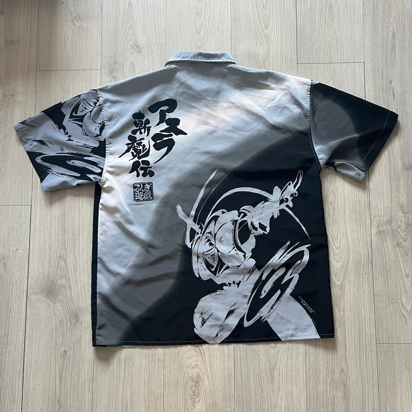 Black and white shirt with Japanese text and design on a wooden floor