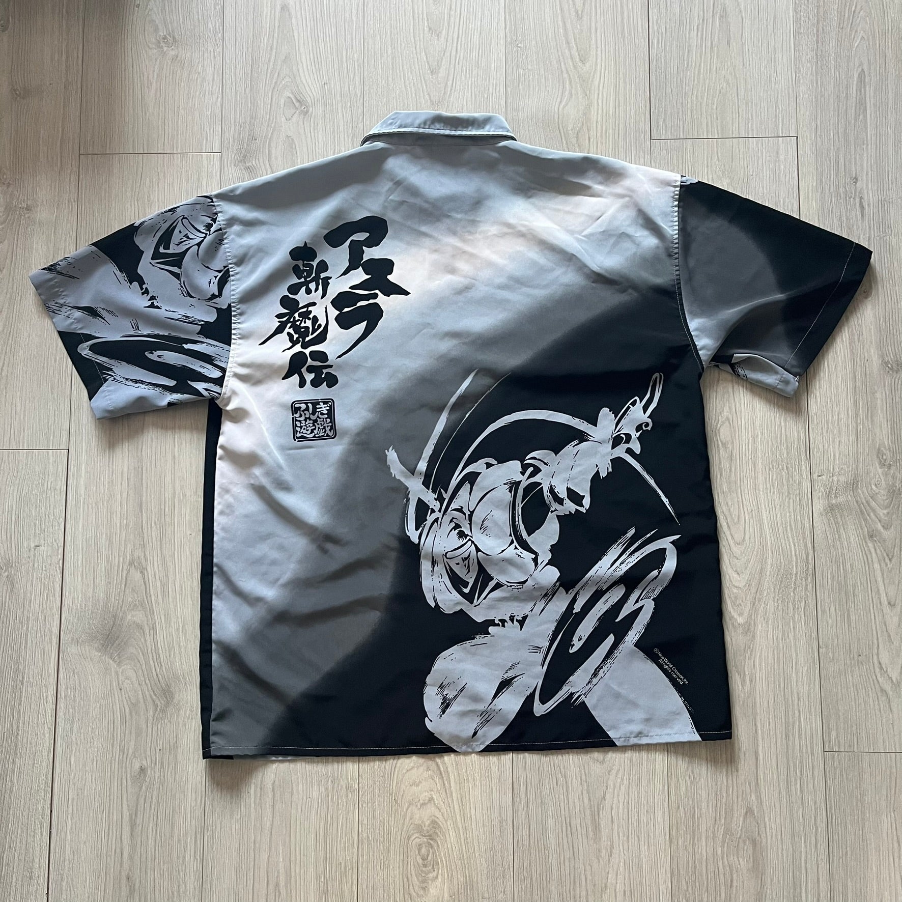 Black and white shirt with Japanese text and design on a wooden floor