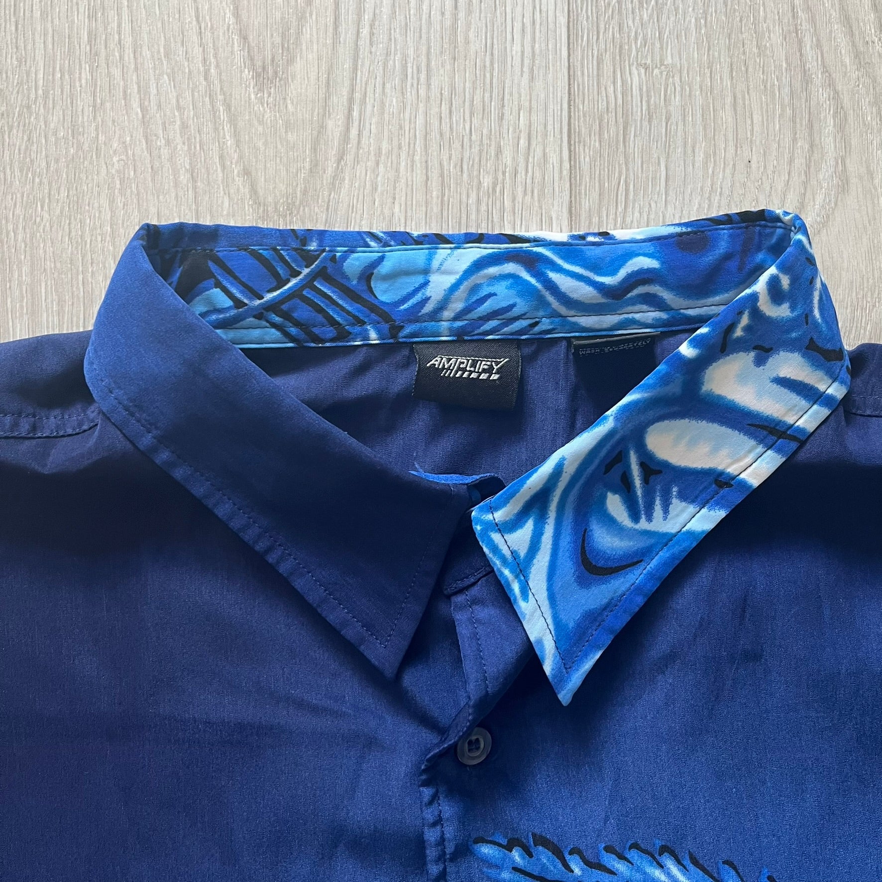 Blue shirt with patterned collar on a wooden surface