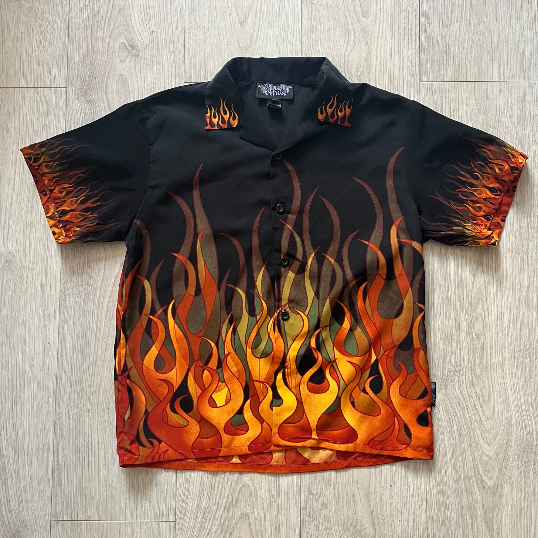 Black shirt with flame pattern on a wooden floor