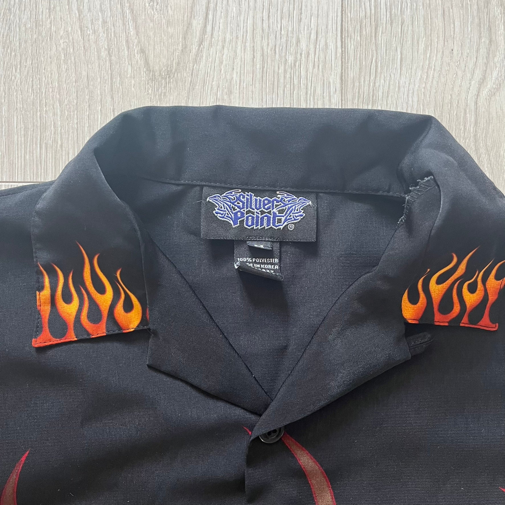Black shirt with flame designs on sleeves and a visible brand label.