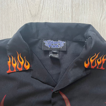 Black shirt with flame designs on sleeves and a visible brand label.