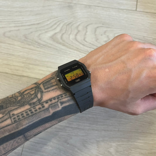 Person wearing a black digital watch on a light wood surface