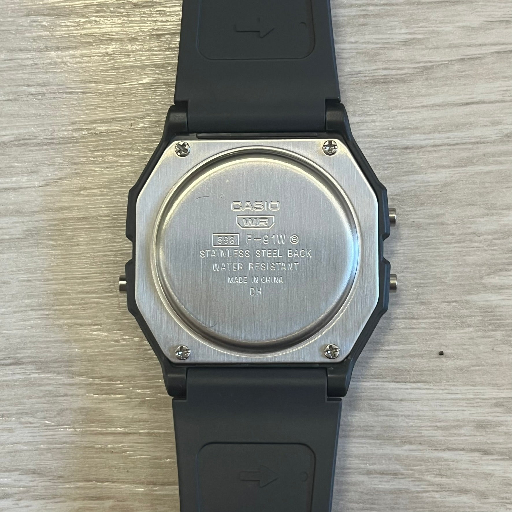 Back view of a Casio watch with black strap on a wooden surface