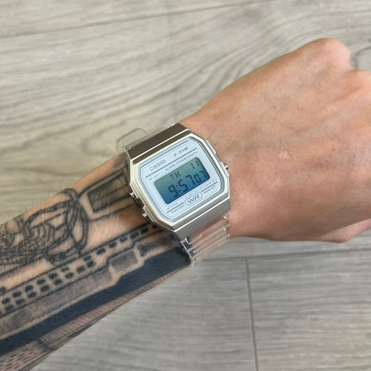 Digital watch on a wrist with tattoos against a wooden floor background