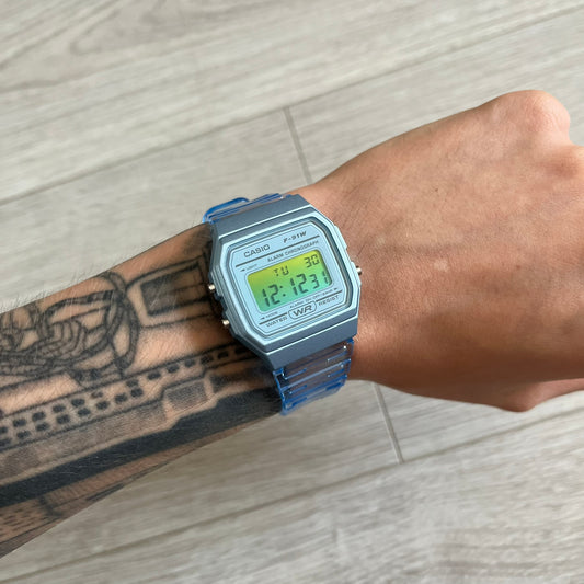 Digital watch on a wrist with a tattooed arm, on a wooden floor background