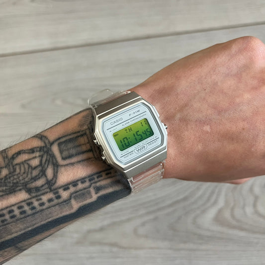 Digital watch on a wrist with tattoos, on a wooden surface