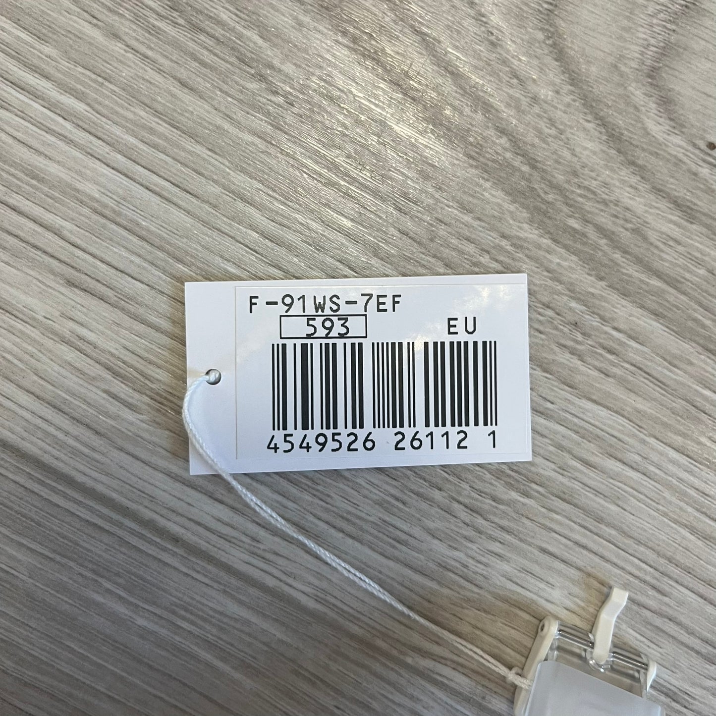 White tag with text and barcode on a textured gray background