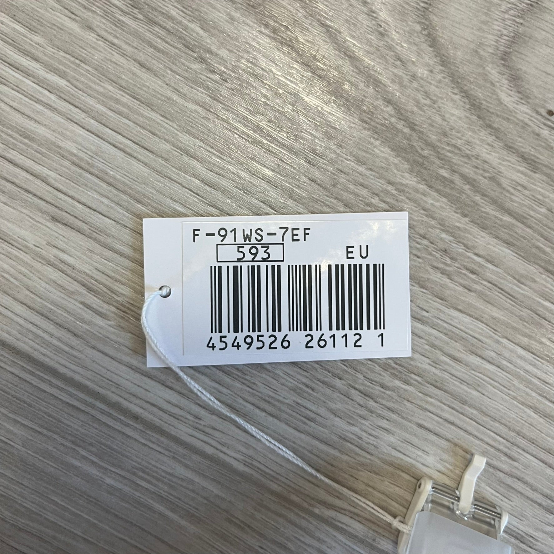 White tag with text and barcode on a textured gray background