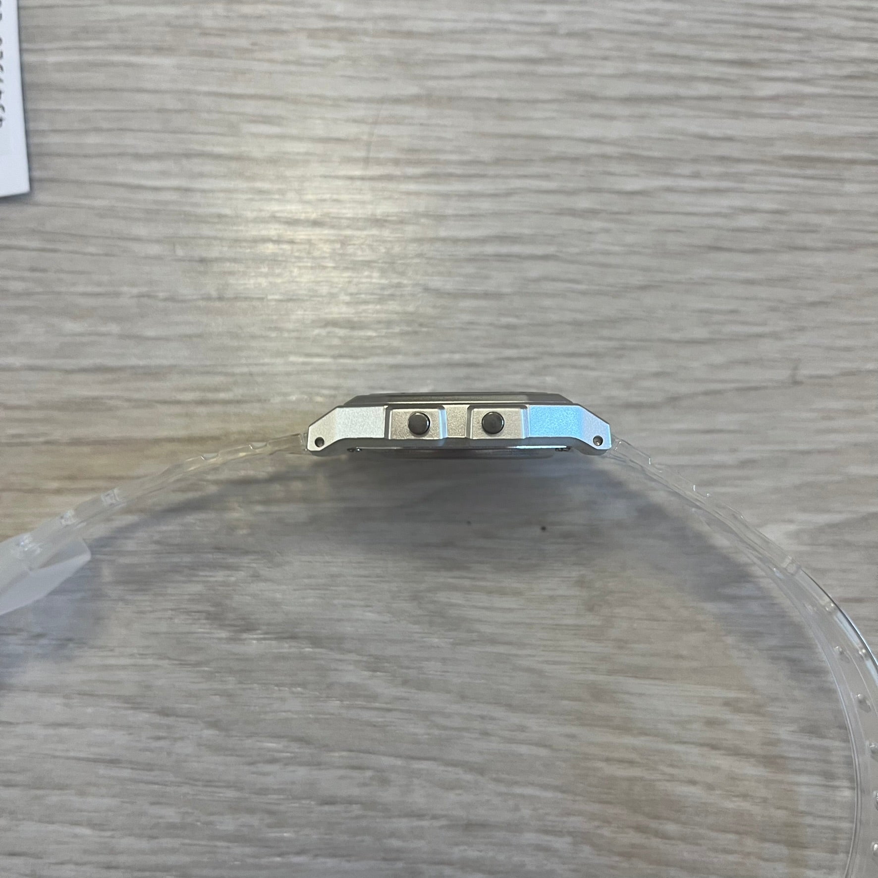 Metallic object on a round, transparent surface with a wooden background