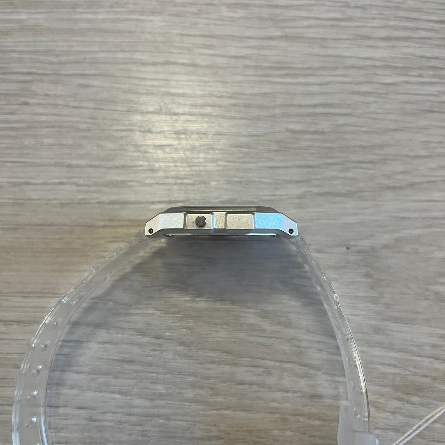 Clear plastic object with metal bracket on a wooden surface