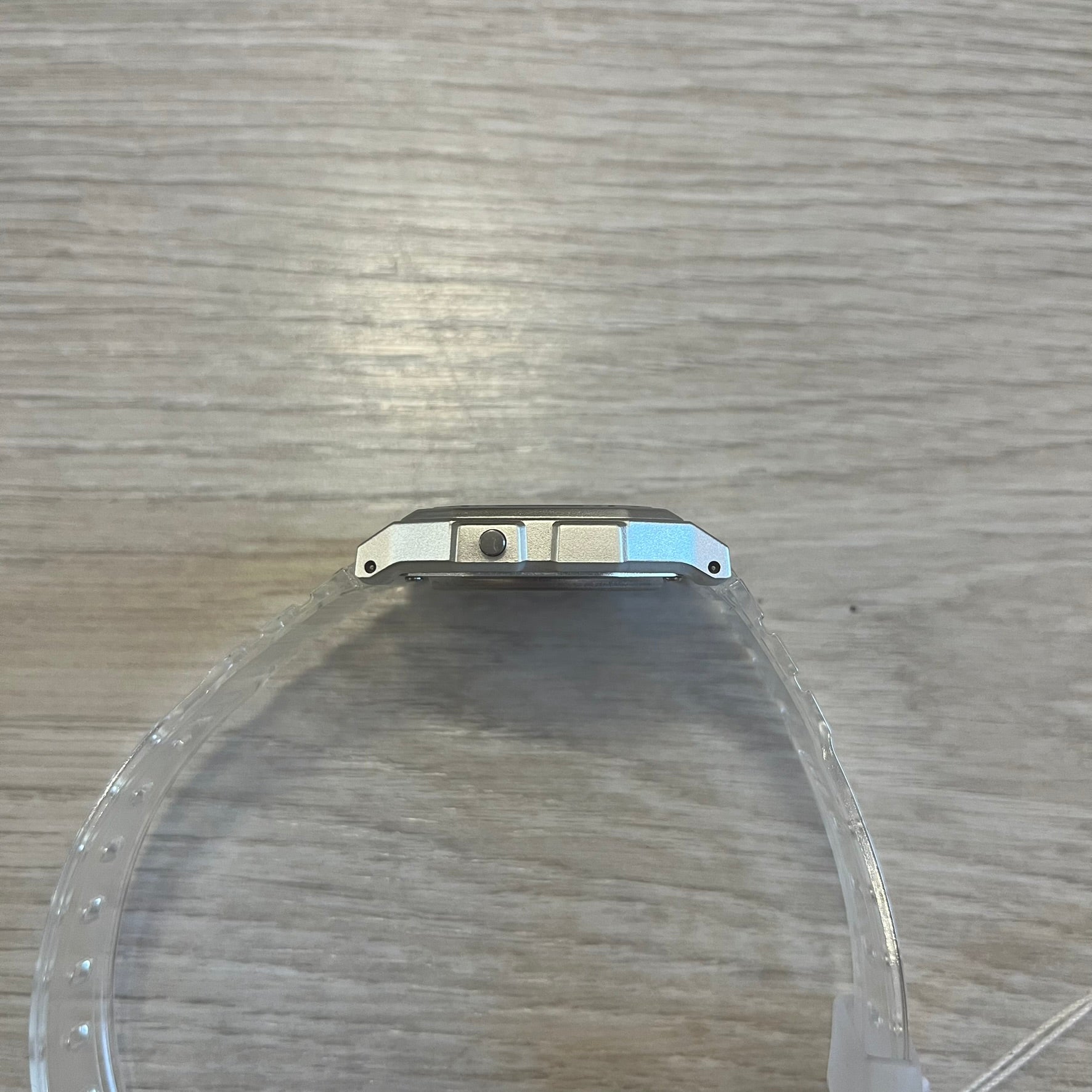 Clear plastic object with metal bracket on a wooden surface