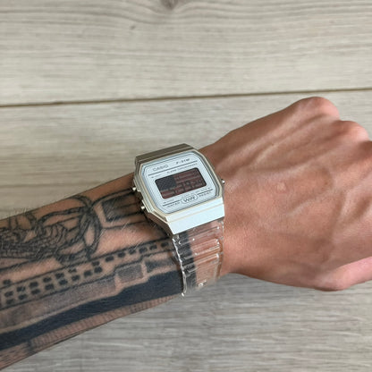 Person wearing a silver Casio watch on a wooden surface