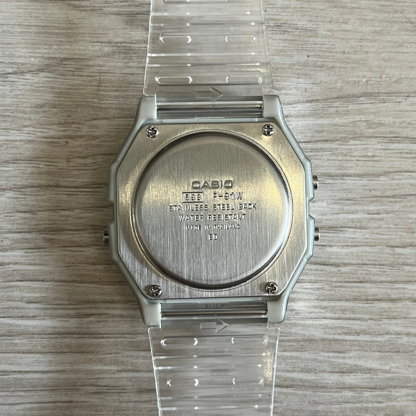 Silver Casio watch with clear plastic strap on a wooden surface