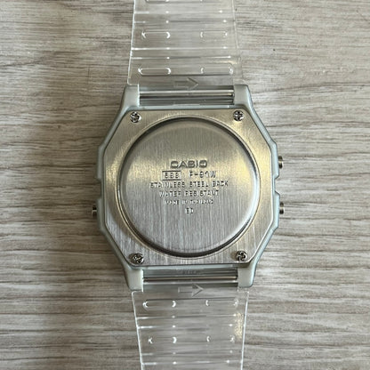 Silver Casio watch with clear plastic strap on a wooden surface