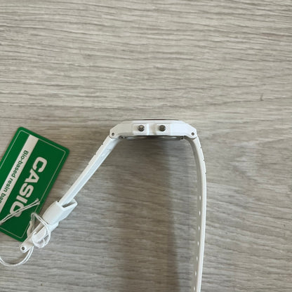 White Casio watch strap on a wooden surface with a green Casio tag.