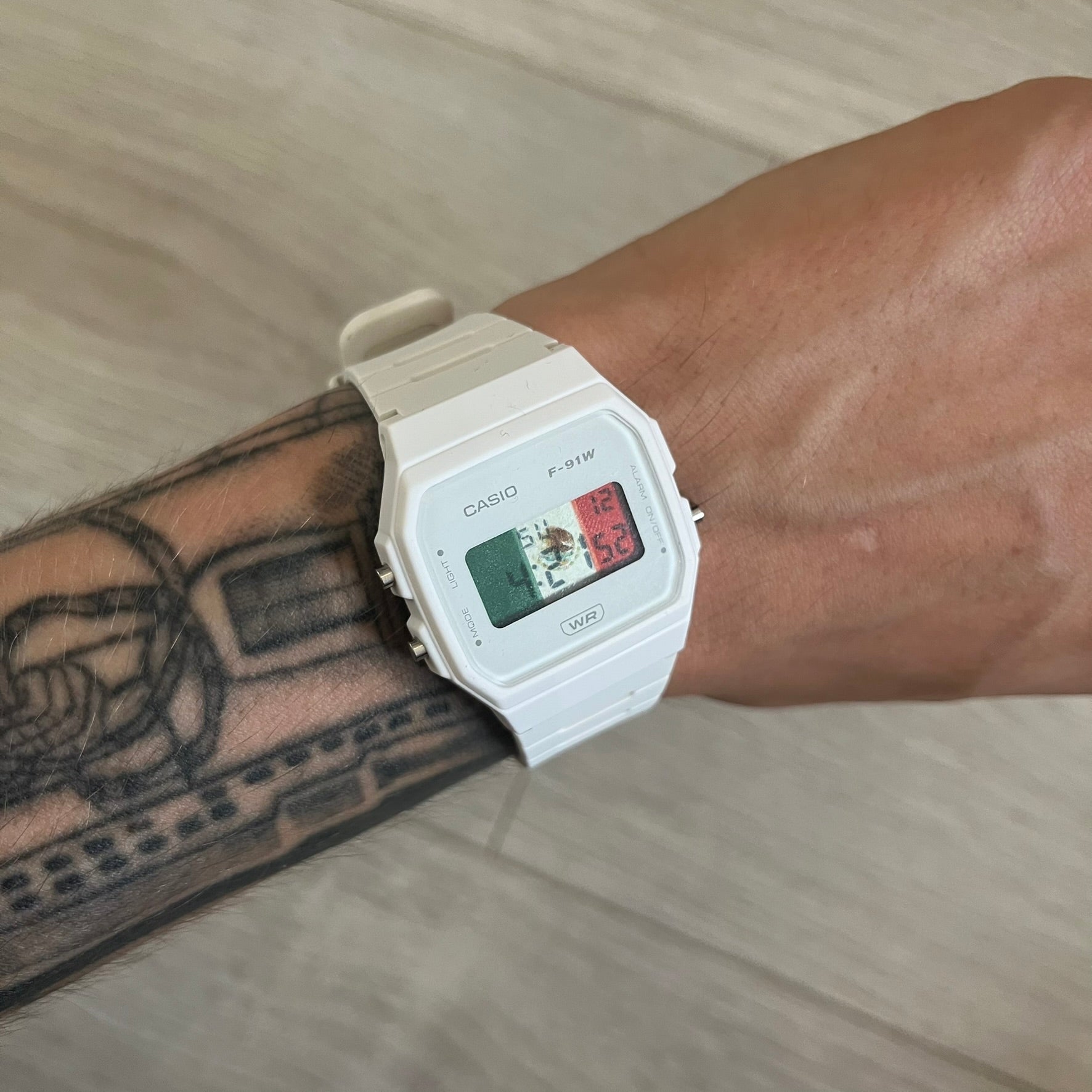 Casio digital watch on a wrist with a tattooed arm
