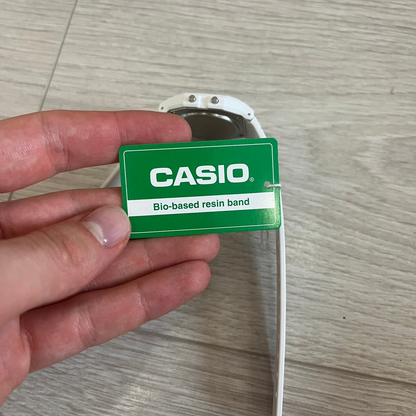 Hand holding a Casio bio-based resin band on a wooden surface