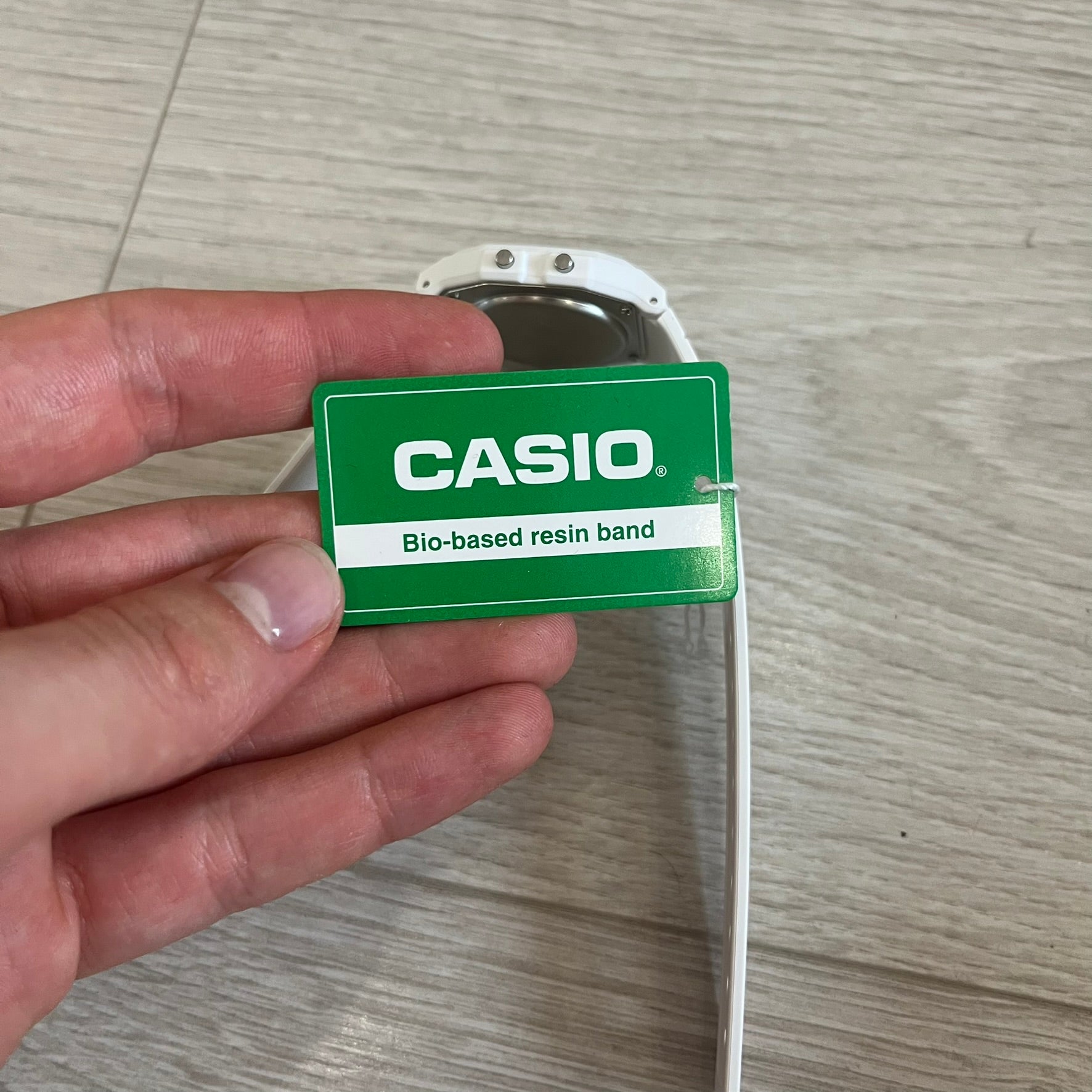 Hand holding a Casio bio-based resin band on a wooden surface