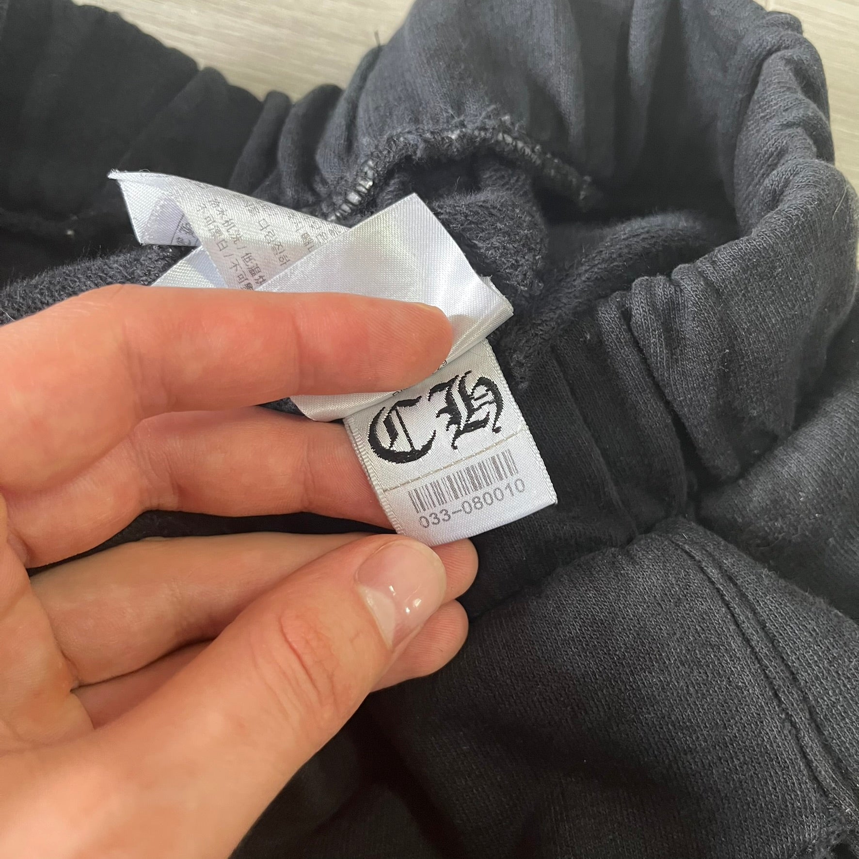 Hand holding a clothing label on a gray garment