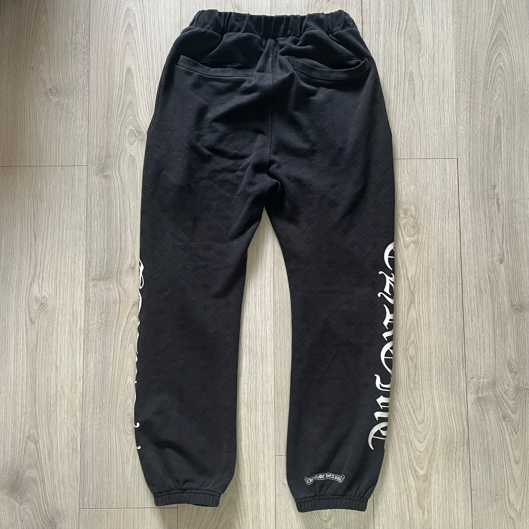Black sweatpants with white text on a wooden floor