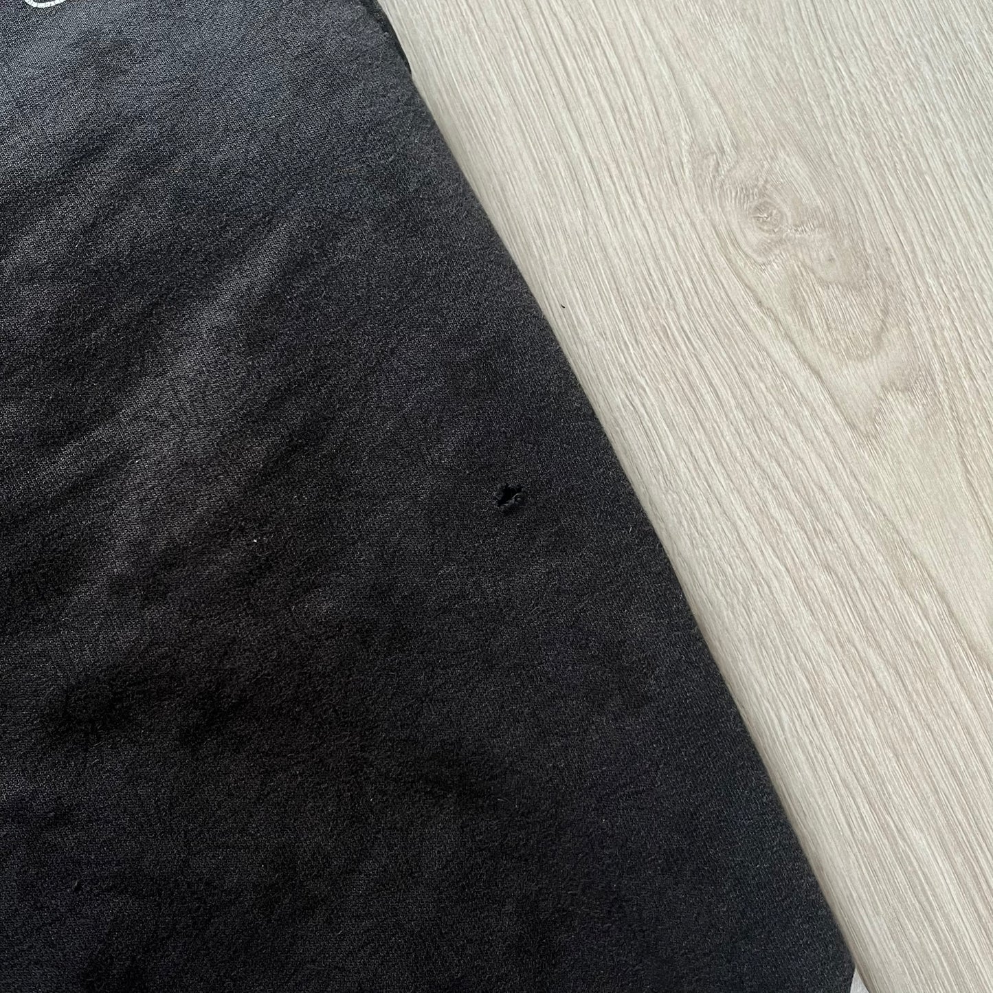 Black fabric with a small hole on a light wood surface