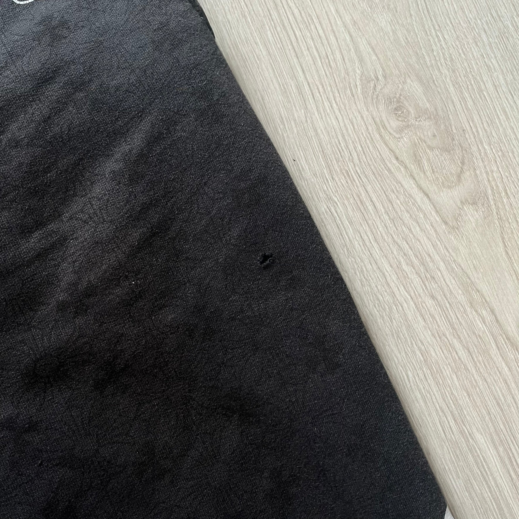 Black fabric with a small hole on a light wood surface