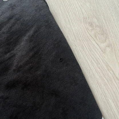 Black fabric with a small hole on a light wood surface
