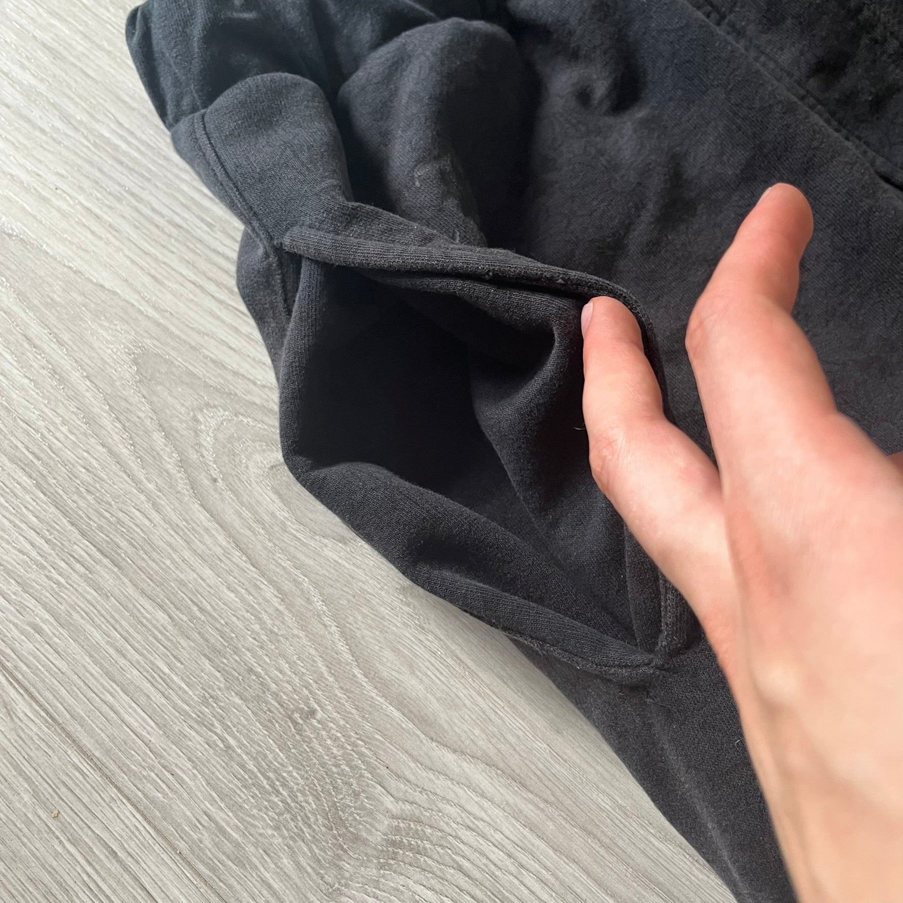 Hand touching dark gray fabric on a wooden surface