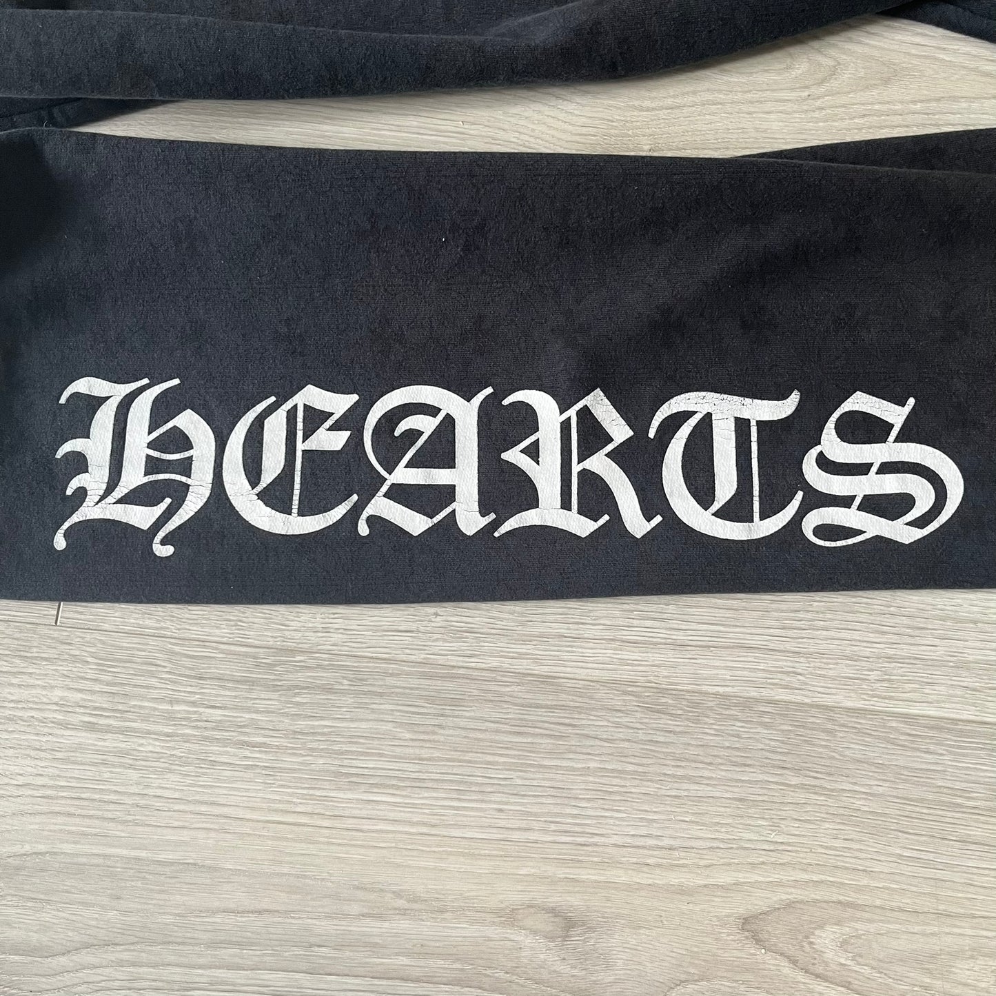 Black fabric with 'HEARTS' printed in white on a wooden surface