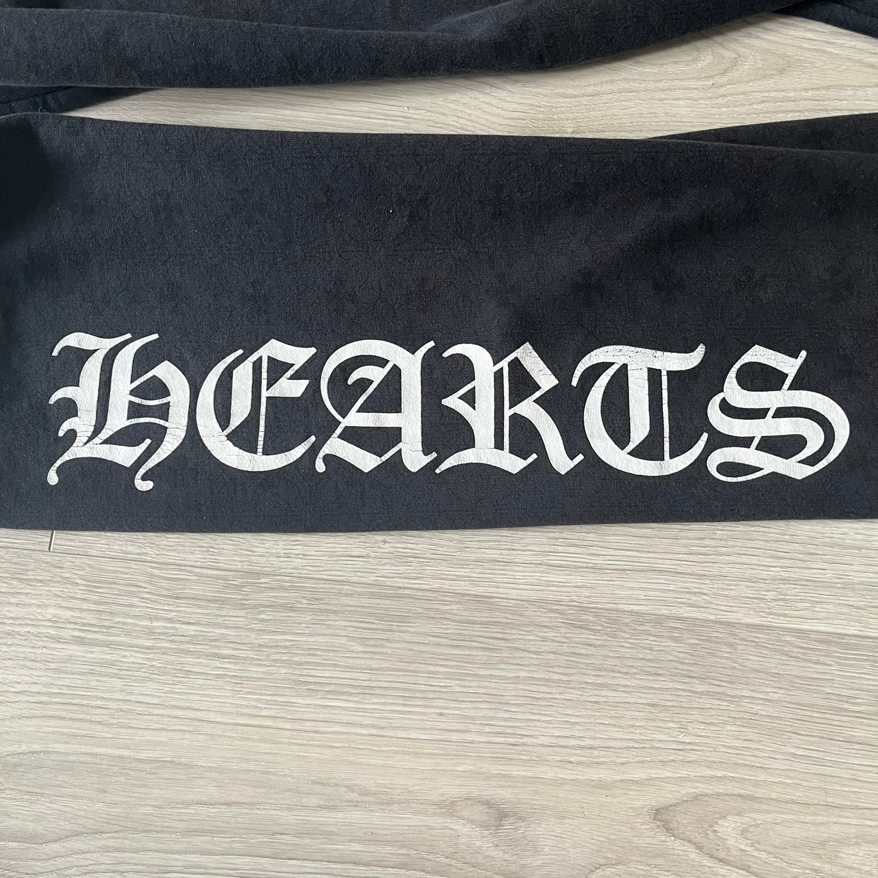 Black fabric with 'HEARTS' printed in white on a wooden surface
