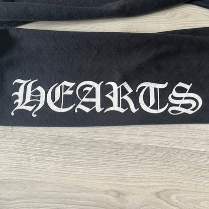Black fabric with 'HEARTS' printed in white on a wooden surface