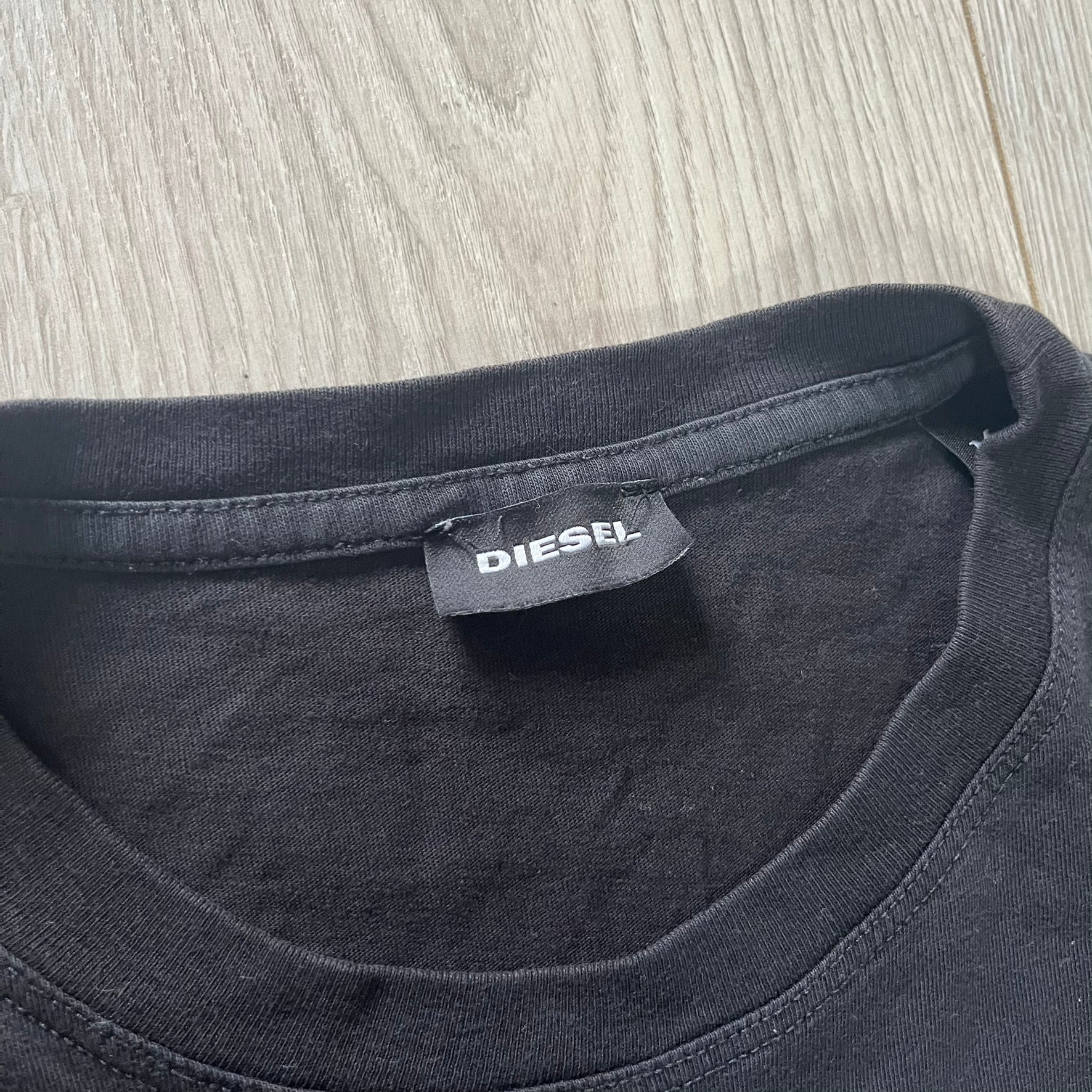 Black t-shirt with a Diesel label on a wooden surface