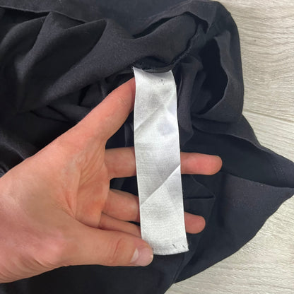 Hand holding a strip of white fabric against dark fabric on a light wooden surface
