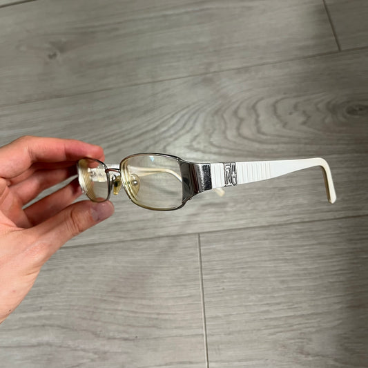 Hand holding a pair of glasses with a wooden surface in the background