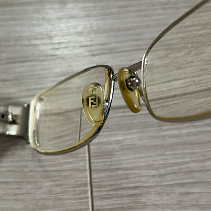 Gold-framed eyeglasses with a logo on a wooden surface