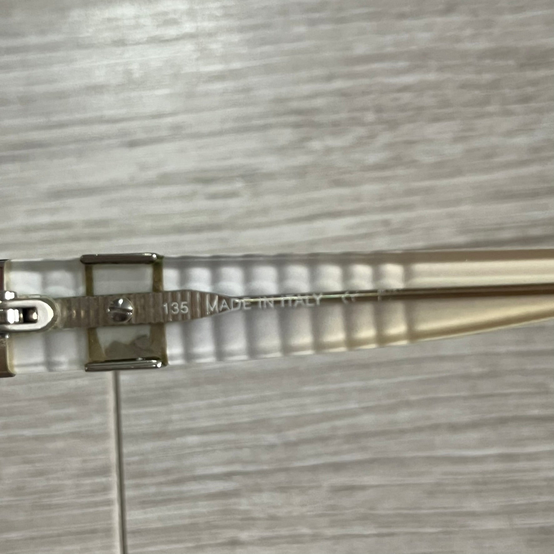 Metallic hairbrush with 'Made in Italy' text on a textured gray background