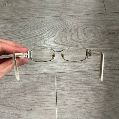 Eyeglasses held by a hand on a wooden floor background