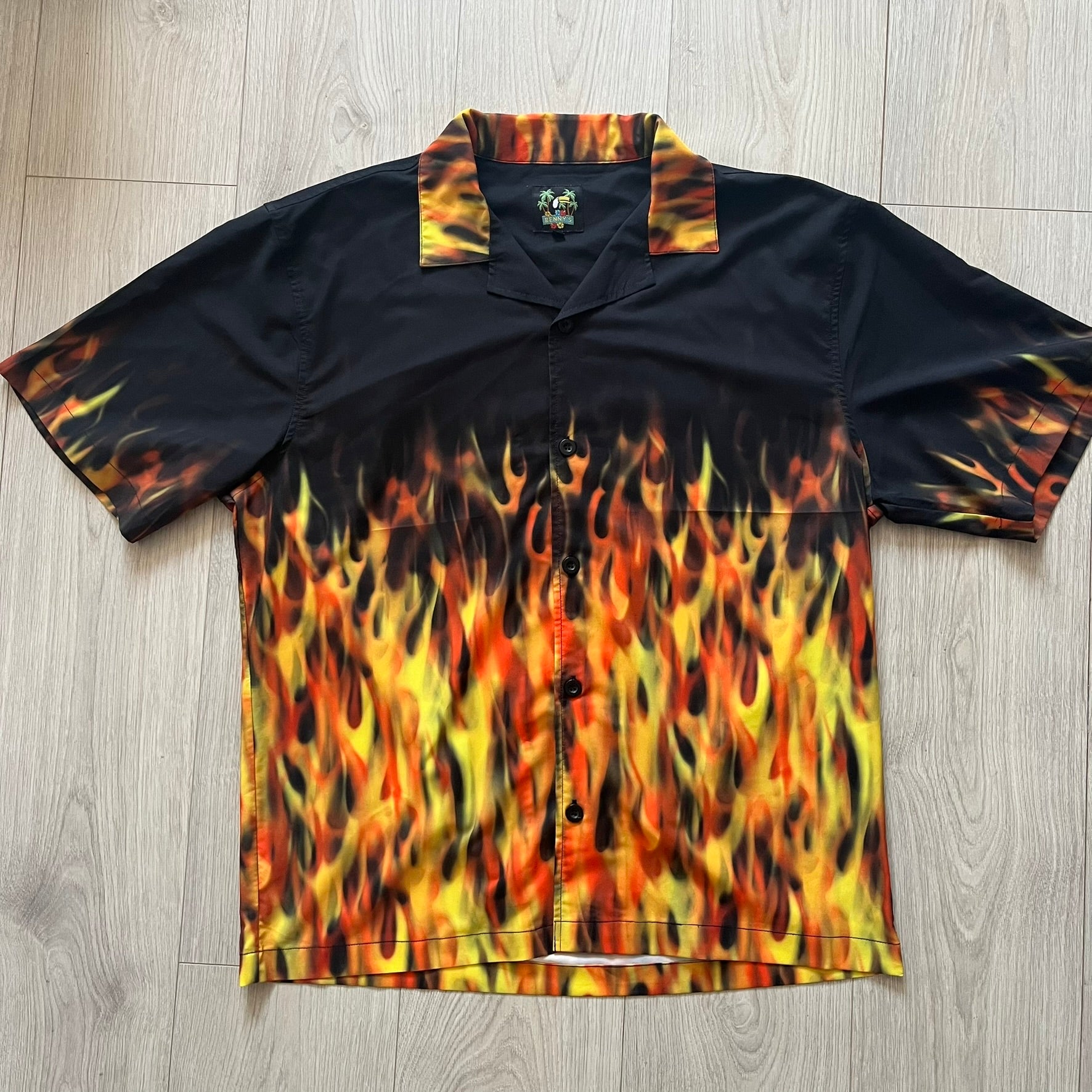 Black shirt with flame pattern on a wooden floor